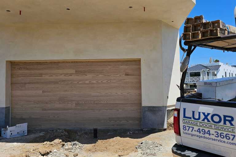 Steel Overlay in New Construction Steel garage door with natural oak wood look overlay installed on a new construction home in Seal Beach, CA
